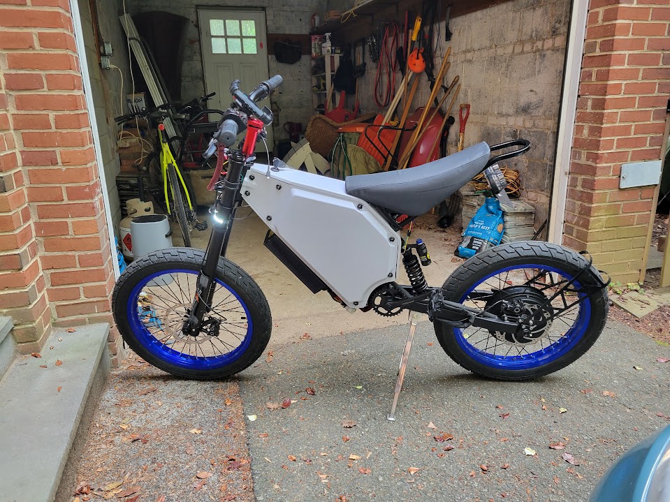 The completed white electric bike in front of a garage